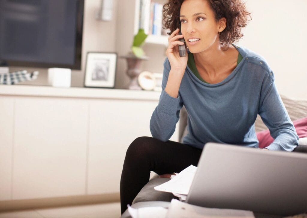 A woman talking on the phone while working at home.