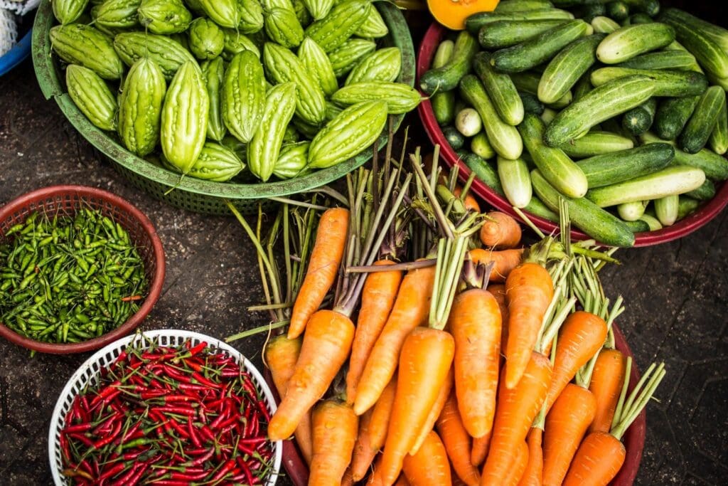 Fresh carrots, cucumbers, and chilies arranged at a market stall.