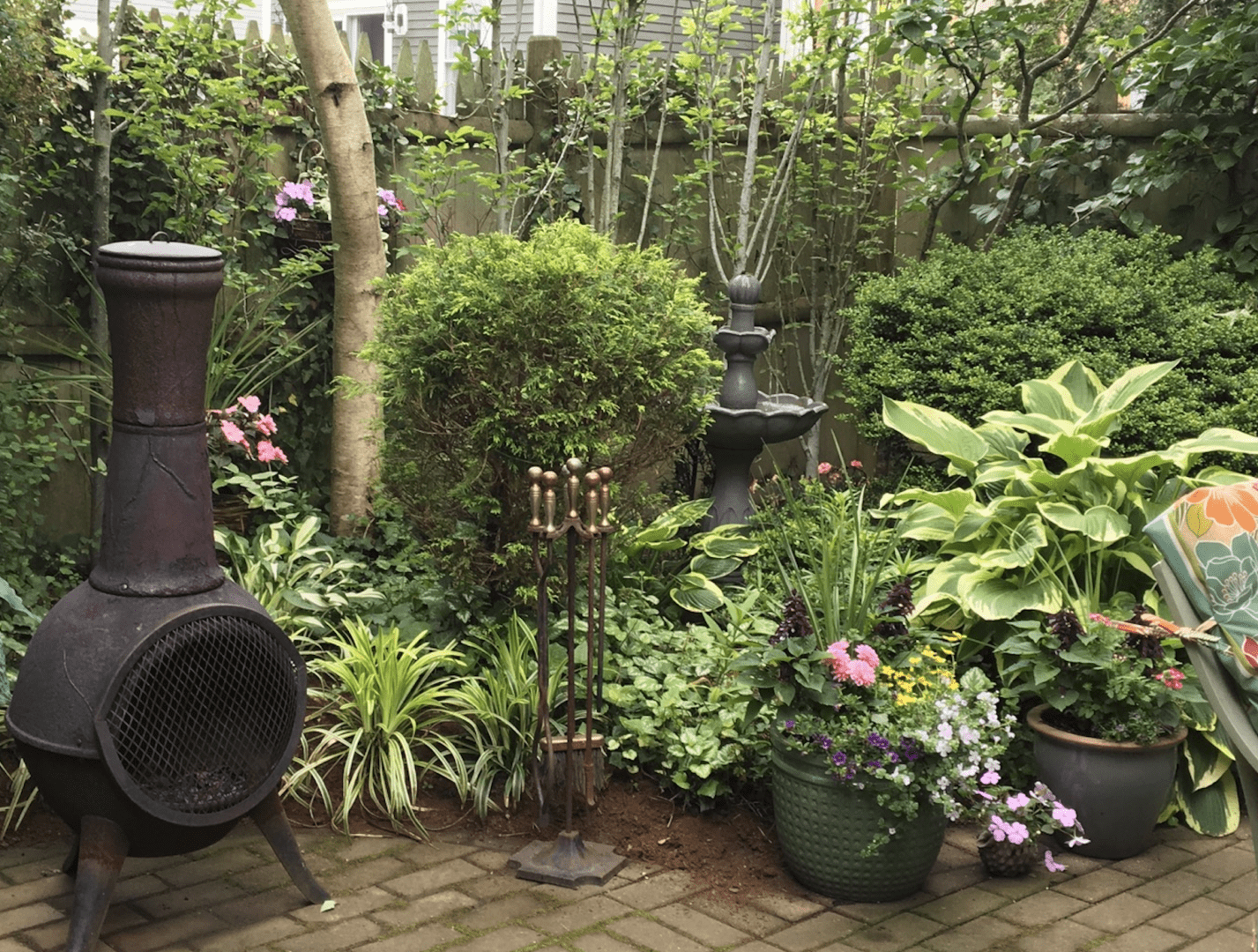 A lush garden corner with green plants and a decorative statue.
