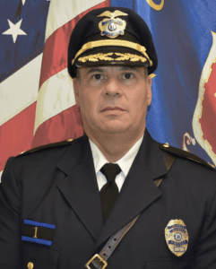 Portrait of a police officer in uniform with an American flag background.