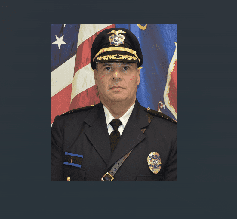 Portrait of a uniformed police officer with flags in the background.