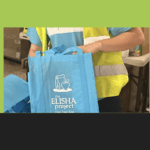 Cars line up at a drive-through food and essentials distribution hosted by The Elisha Project in Pawtucket