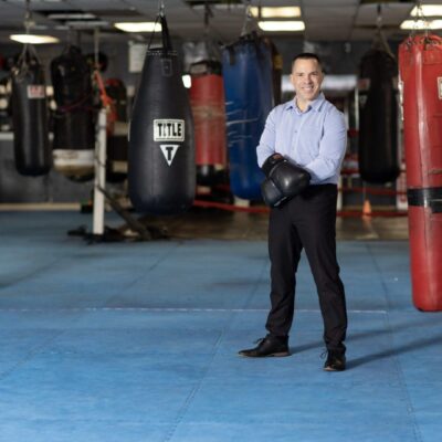 A man standing in front of a boxing ring with punching bags.