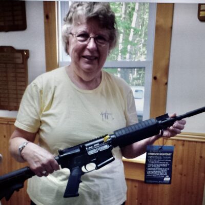 A woman holding a rifle in a room.