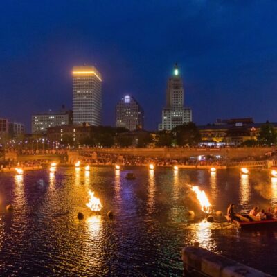 Nighttime cityscape with fiery water display.