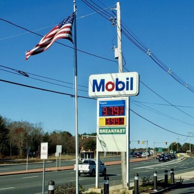 A mobil gas station with an american flag on the side of the road.