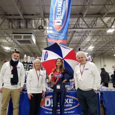 A group of people standing in front of a table with an umbrella.