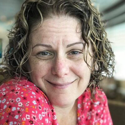 A woman with curly hair smiling at the camera.