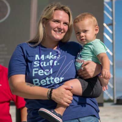 A woman holding a baby wearing a t - shirt that says make stuff feel better.