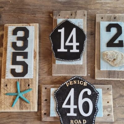 A set of wooden house numbers with starfish and seashells on them.