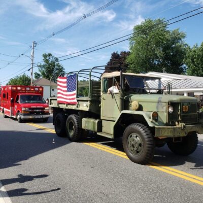 Patriotic parade with military truck and ambulance.