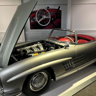 A silver mercedes benz sl roadster is on display in a showroom.