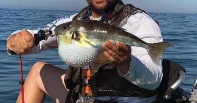 A man holding up a fish in the water.