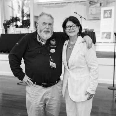 Two people smiling and posing together indoors in casual and formal attire.
