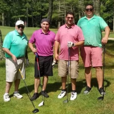 Four men posing for a photo on a golf course.