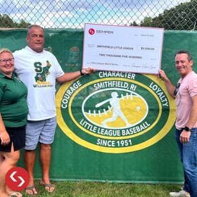A group of people standing in front of a sign with the Little League World Series check.