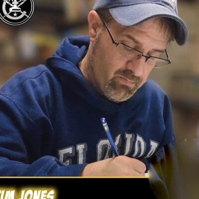 Tim Jones is writing on a piece of paper while attending RI Comic Con.