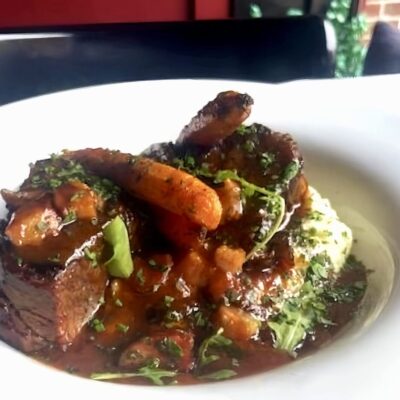 A plate of beef stew with carrots and mashed potatoes.