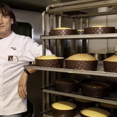 A man standing in front of some cakes on shelves.