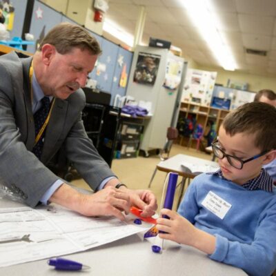 A man in a suit sits at a table with a boy.