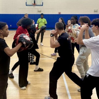A group of young people practicing martial arts for self-defense in a gym.