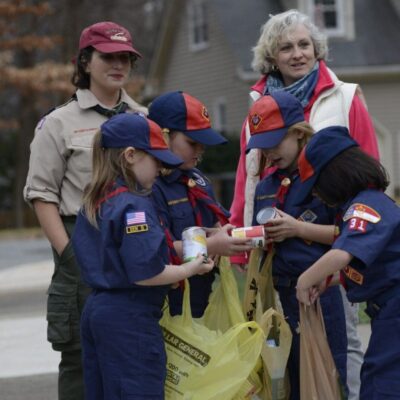 Girl Scouts collecting canned goods.