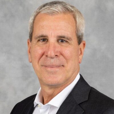 A man with white hair and wearing a suit.