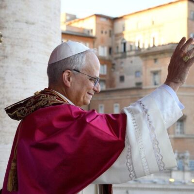 A pope waving from a balcony during daylight.