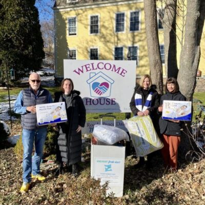 A group of people standing in front of a house holding signs.