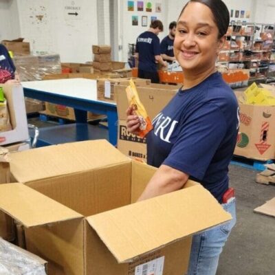 Woman smiling while packing items into boxes at a volunteer event.