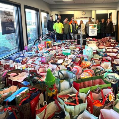 A group of people standing in front of a room full of BankRI bags.