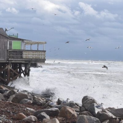 Stormy sea crashing against seaside building.