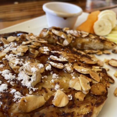 A plate of french toast with almonds and fruit.