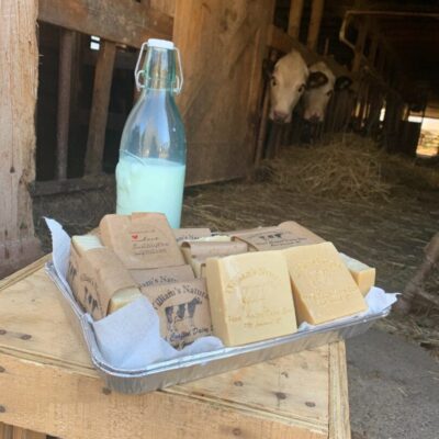 A tray of soap on a wooden table next to a bottle of milk.
