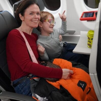 A smiling woman and child seated together on an airplane.