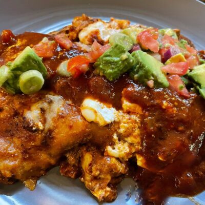Mexican enchiladas with guacamole on a plate.