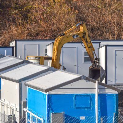A blue and white building with a yellow excavator in the back.