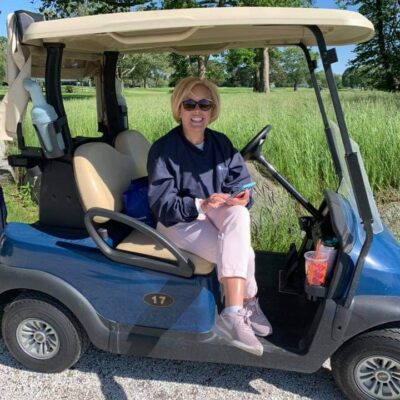 A woman sitting in a golf cart.