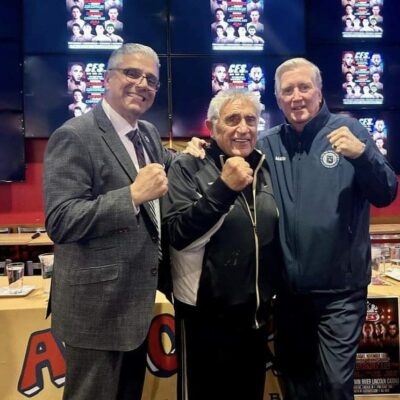 Three men posing for a picture in a boxing ring.
