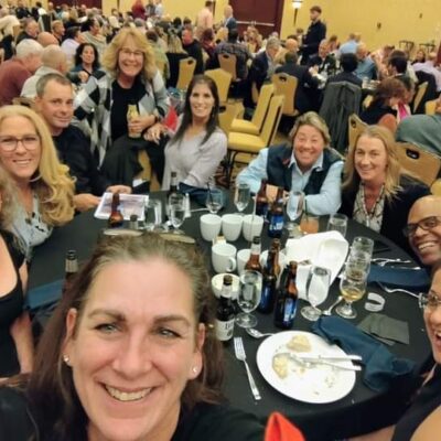 A group of people sitting at tables with wine glasses.