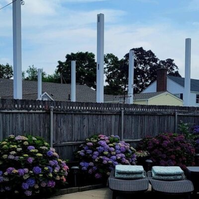 White posts behind a wooden fence with hydrangeas.