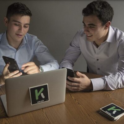 Two men sitting at a table looking at their phones.