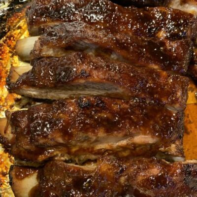 Bbq ribs in foil on a baking sheet.