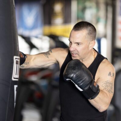 A man is punching a boxing bag in a gym.