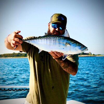A man holding up a fish on a boat.