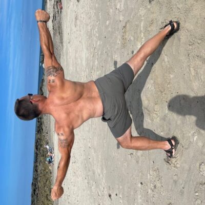 A man doing a fitness yoga pose on the beach.