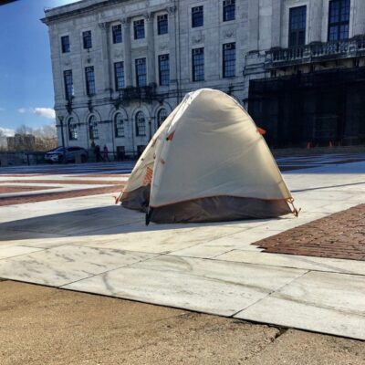 A tent is set up in front of a building.