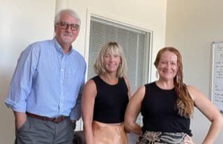 Three people posing for a picture in an office during a grantwriting session.