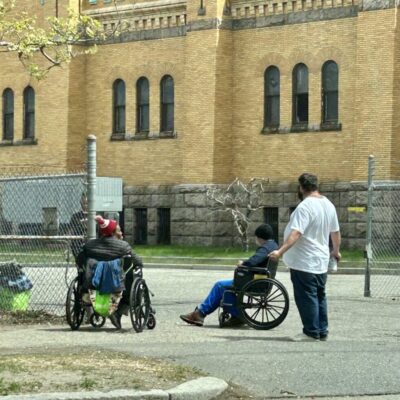A group of people in wheelchairs in front of a building.