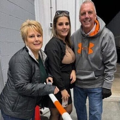 A woman holding a baseball bat with two men.